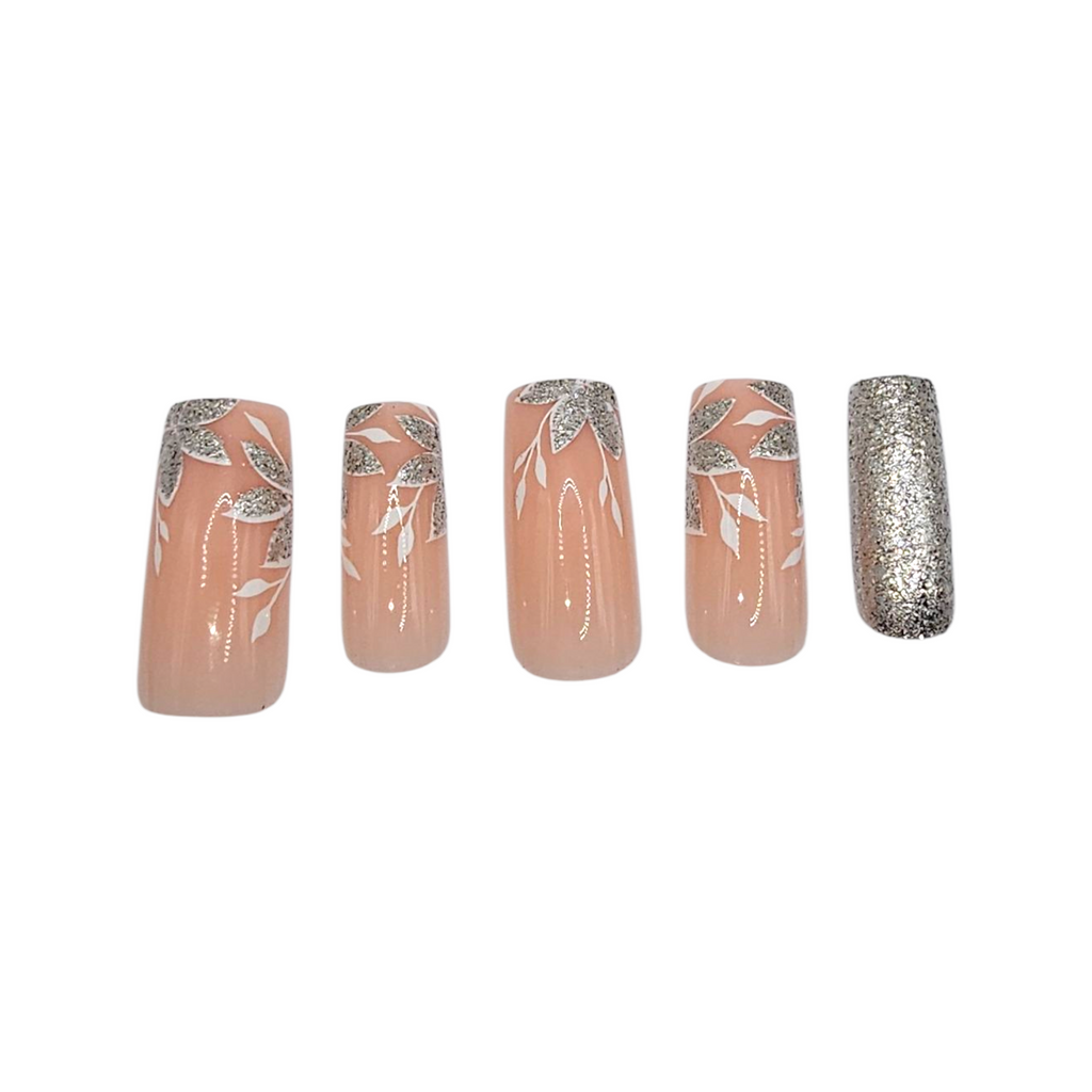 Close-up of Garden Party press-ons – nude base with white floral and silver glitter accents – Rodeo & Wilshire Beauty