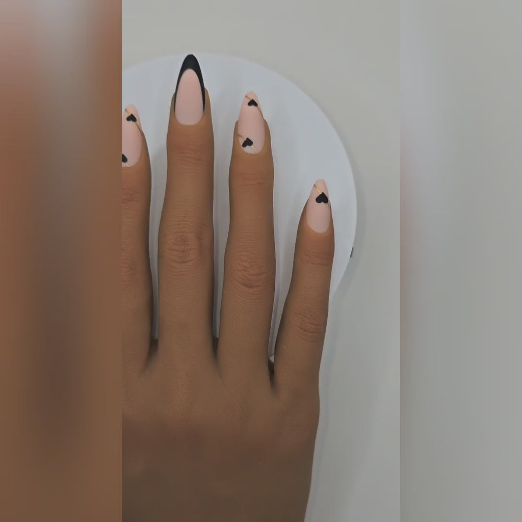 Application video showing Kiss & Tell black & nude almond press-on nails with tiny hearts – flirty date night styling – Rodeo & Wilshire Beauty